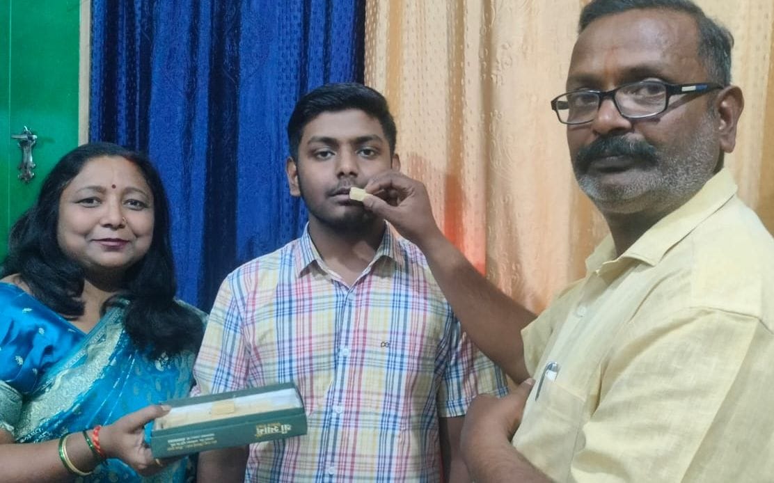 सीबीएसई की जिला टॉपर शिजा को मिठाई खिलाते परिजन। स्रोत: स्वयं