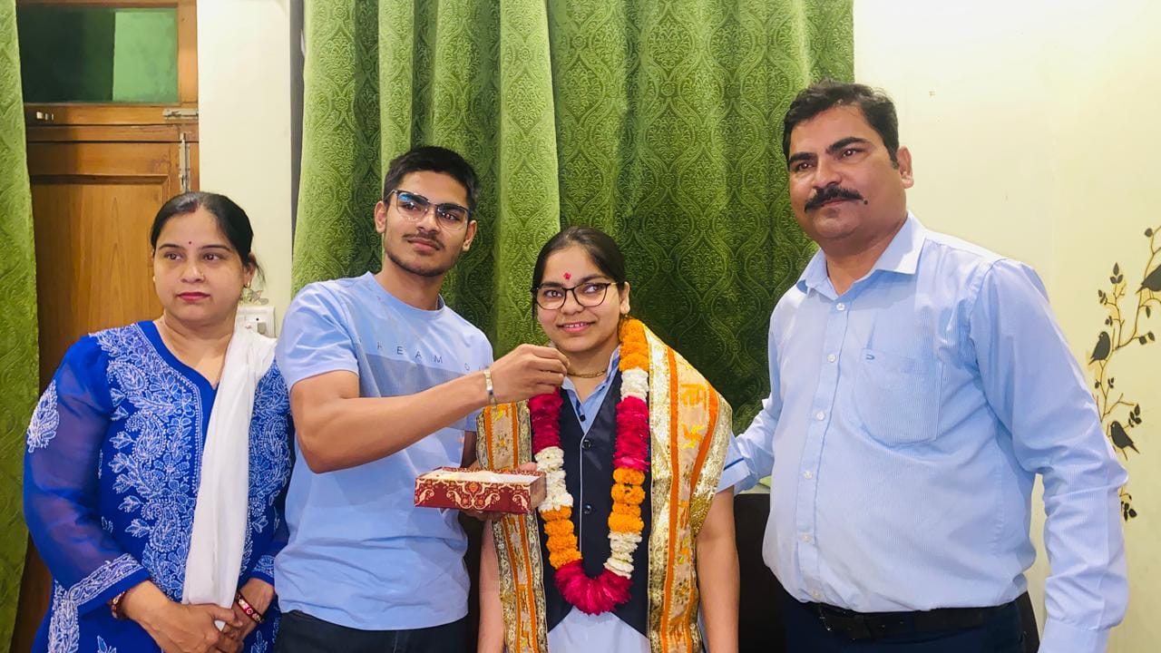 सीबीएसई की जिला टॉपर शिजा को मिठाई खिलाते परिजन। स्रोत: स्वयं