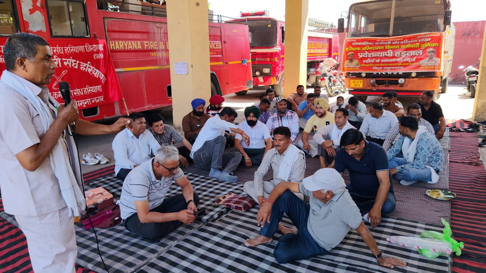 दमकल केंद्र पर हड़ताल पर बैठे कर्मचारियों को संबोधित करते वक्ता। संवाद दमकल केंद्र पर हड़ताल पर बैठे कर्मचारियों को संबोधित करते वक्ता। संवाद
