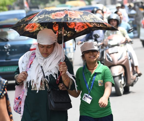 शुक्रवार को तेज धूप से बचती महिलाएं। 