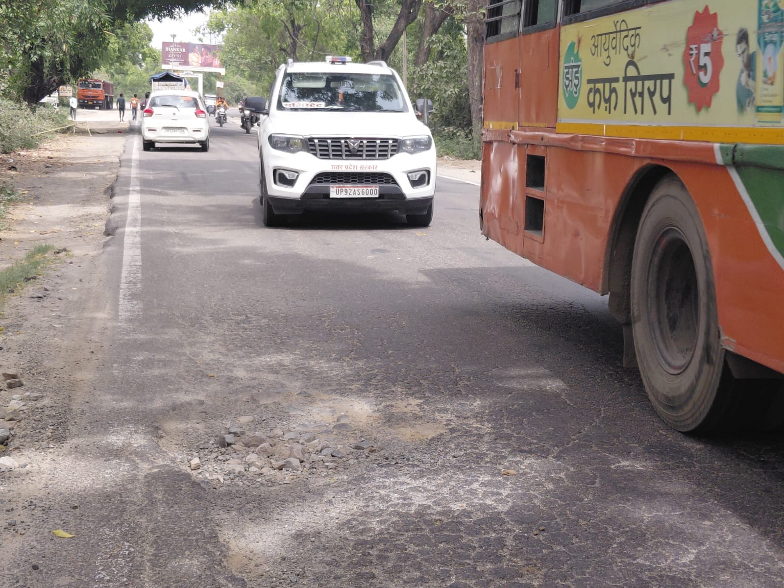 शहर से सटे इलाके में पीलीभीत-टनकपुर हाईवे पर गड्ढे से बचकर गुजरता वाहन। संवाद