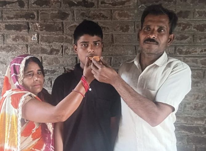 सत्यदेव को मिठाई खिलातीं मां रिंकी। स्रोत : स्वयं