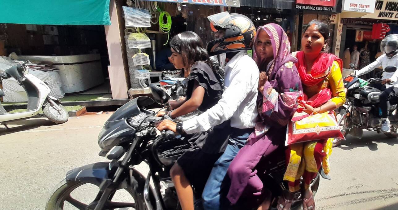 चौक पर बिना हेलमेट के तीन सवारी ले जाता युवक।