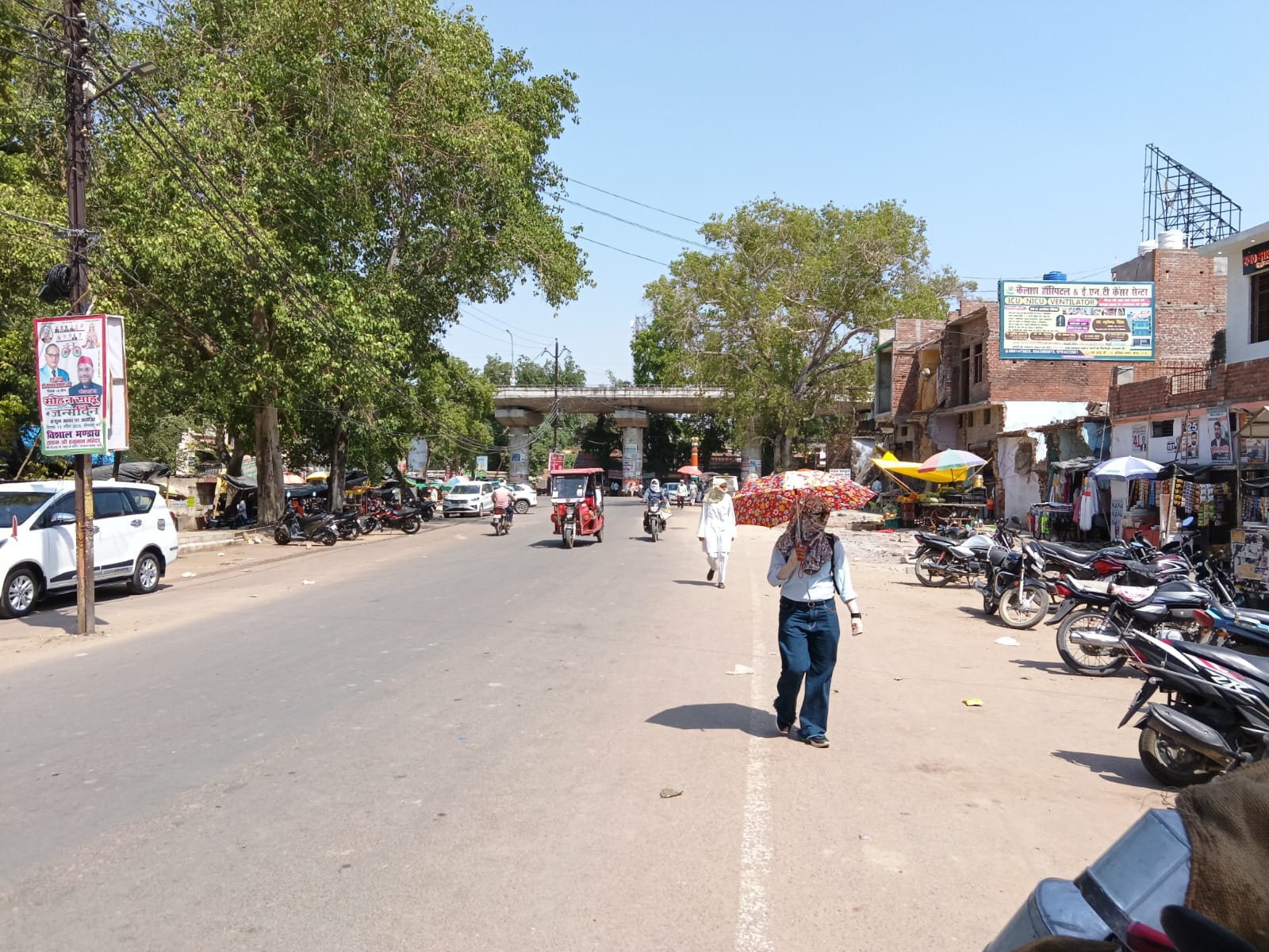 फोटो- 16 शहर के कोतवाली रोड पर छाता लगाकर निकलतीं युवती। संवाद