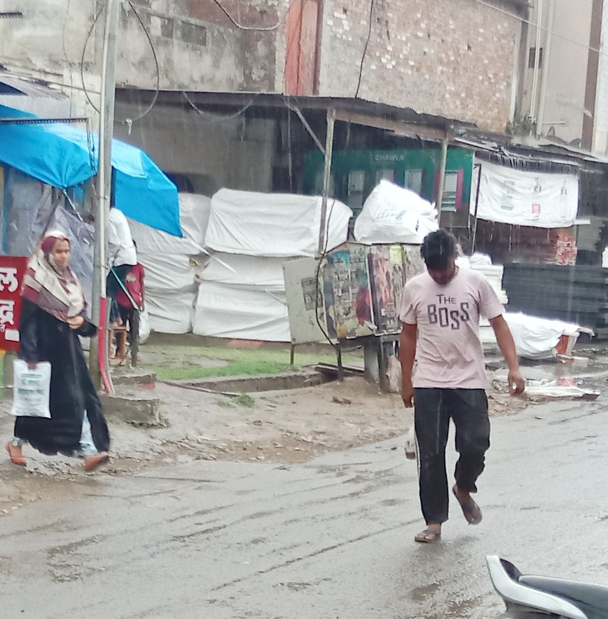 बारिश से बचाने के लिए सामान को ढकते महिला। संवाद