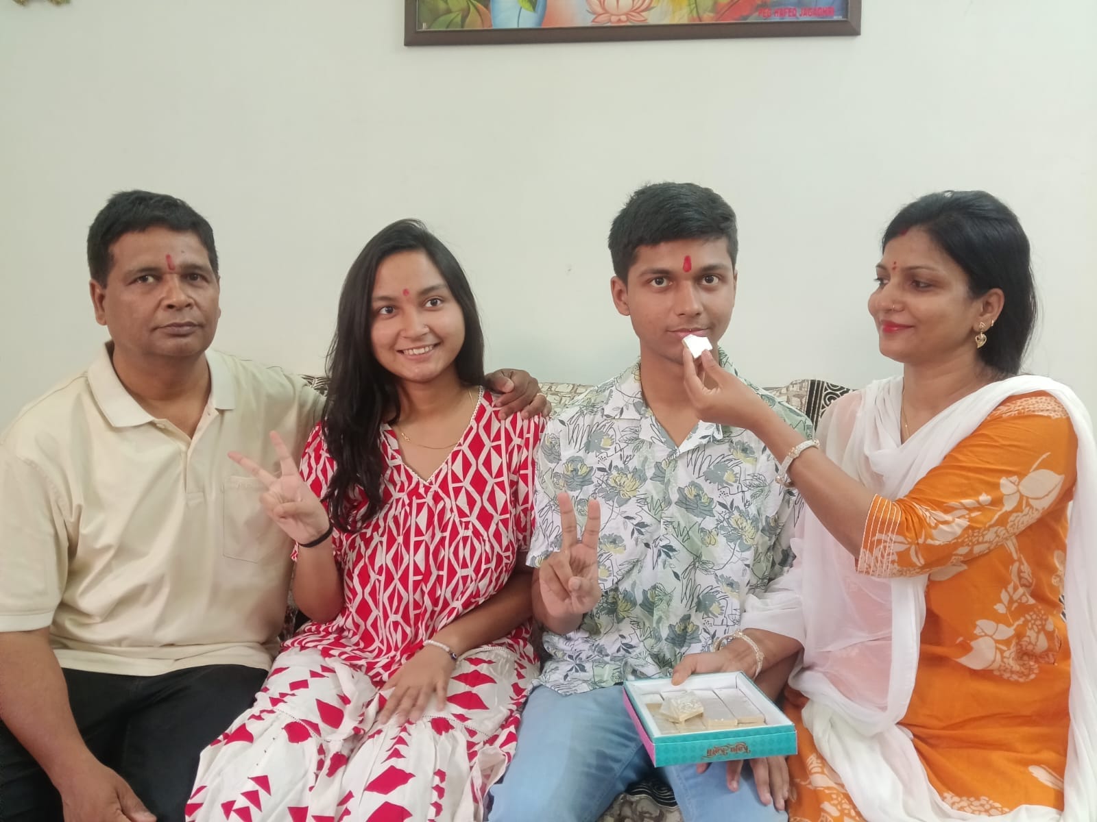 फोटो-11- आईसीएसई बोर्ड हाई स्कूल की टॉपर अनुष्का को मिठाई खिलाते पिता सुबोध कुमार मां साधना साथ