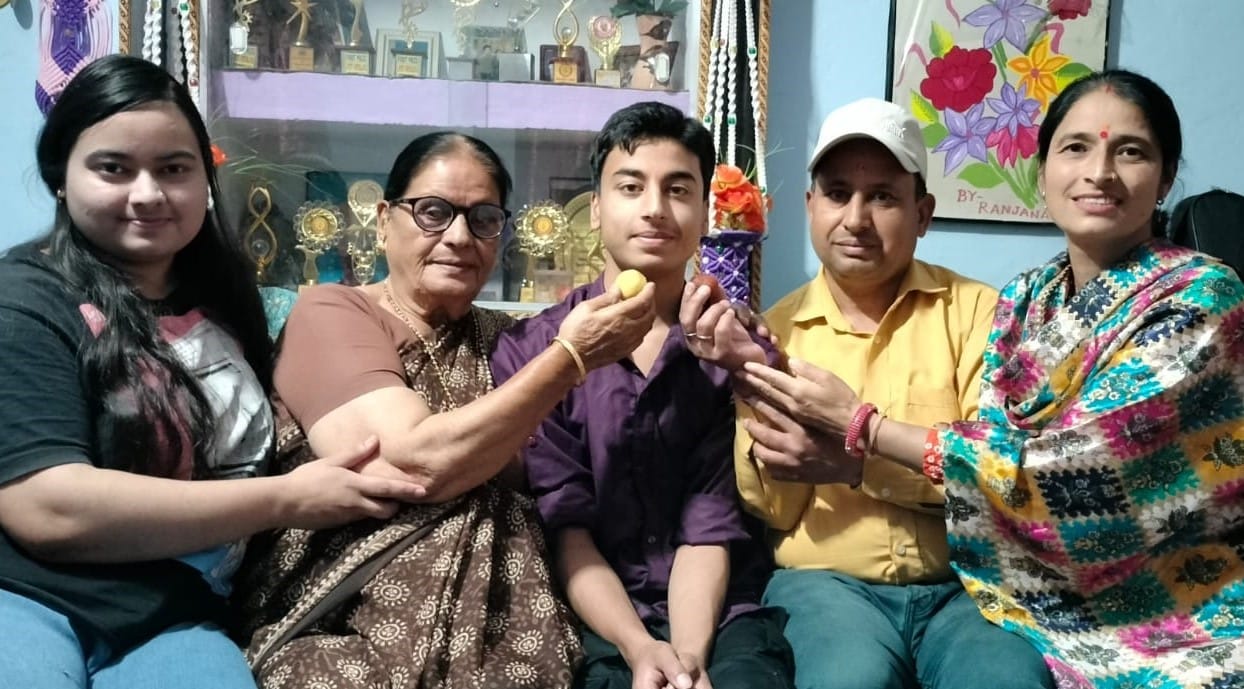 गोपेश्वर के क्राइस्ट एकेडमी के छात्र स्मयन कोे को मिठाई खिलातीं उसकी माता। स्रोत: विद्यालय प्र