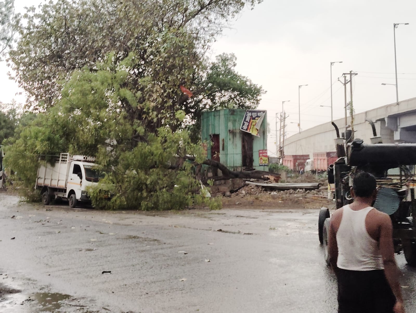 पड़री क्षेत्र में दाढ़ीराम में तेज आंधी के बीच सड़क पर गिरे टीन शेड उठाते ग्रामीण।-संवाद।