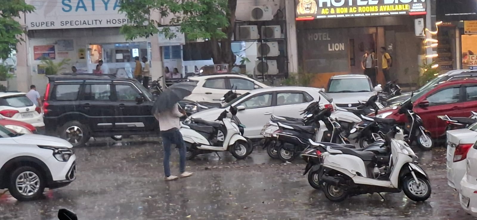 बारिश के बीच शहर के मॉडल टाउन से जाते लोग। संवाद