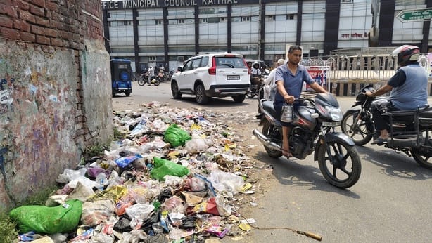 करनाल रोड पर लगे कचरे के ढेर के पास से मुंह ढक कर गुजरती छात्राएं। संवाद