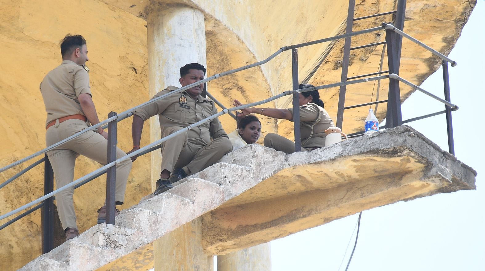 महिला को पानी की टंकी से उतारती पुलिस व मौजूद भीड़।