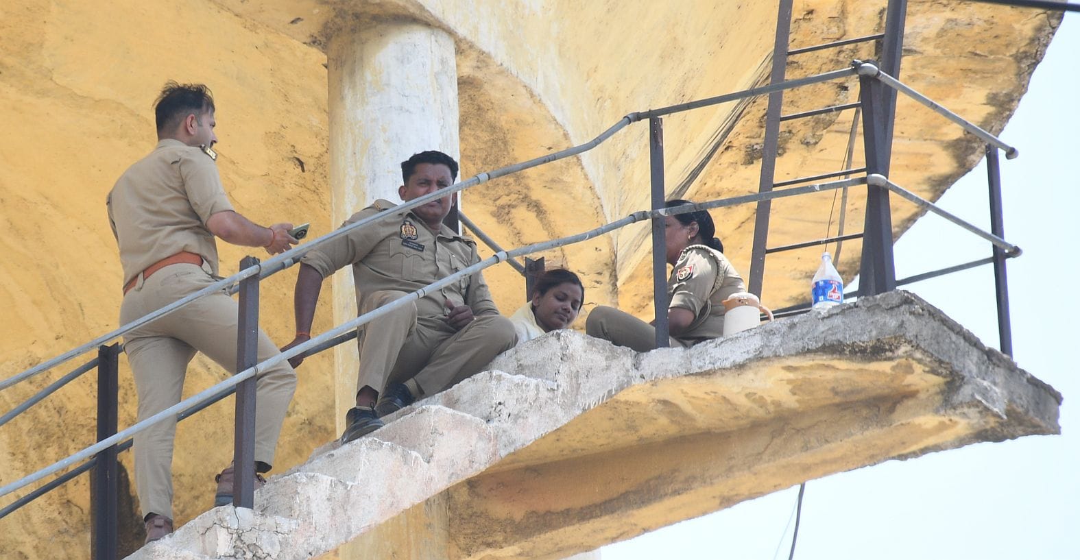 महिला को पानी की टंकी से उतारती पुलिस व मौजूद भीड़।