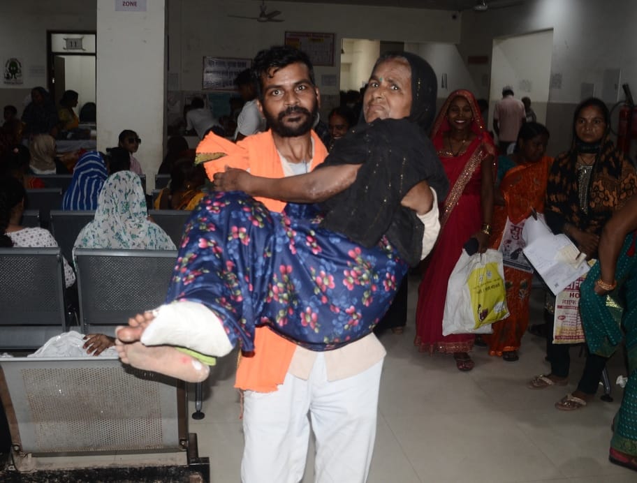 मेडिकल कॉलेज में स्ट्रेचर न मिला तो मां को गोद में उठाकर ओपीडी में लेकर जाता युवक। संवाद
