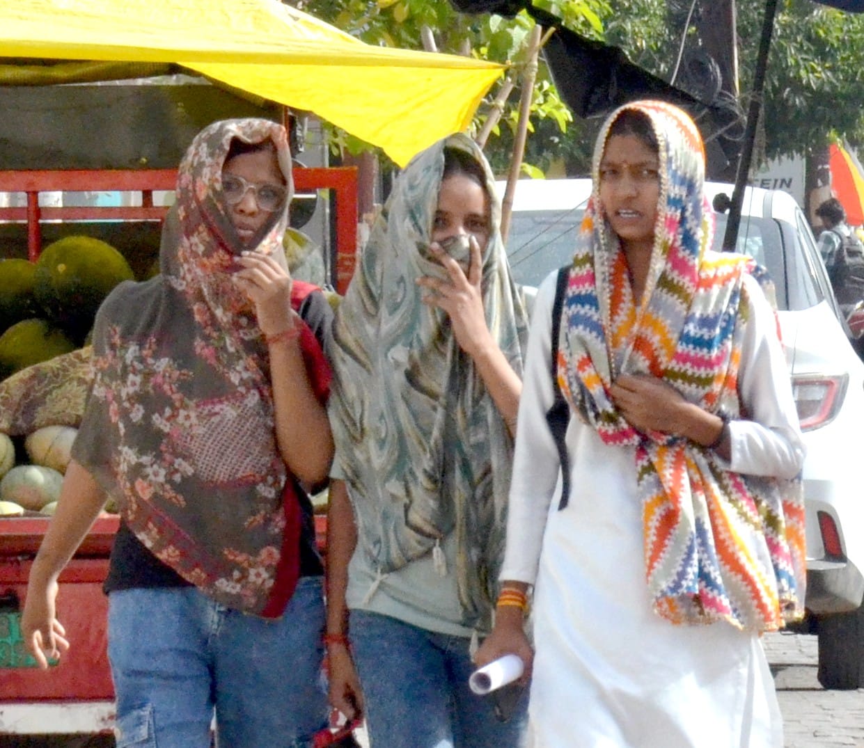 आगरा रोड पर तेज धूप में दुपट्टा ओढ़कर जातीं युवतियां।
