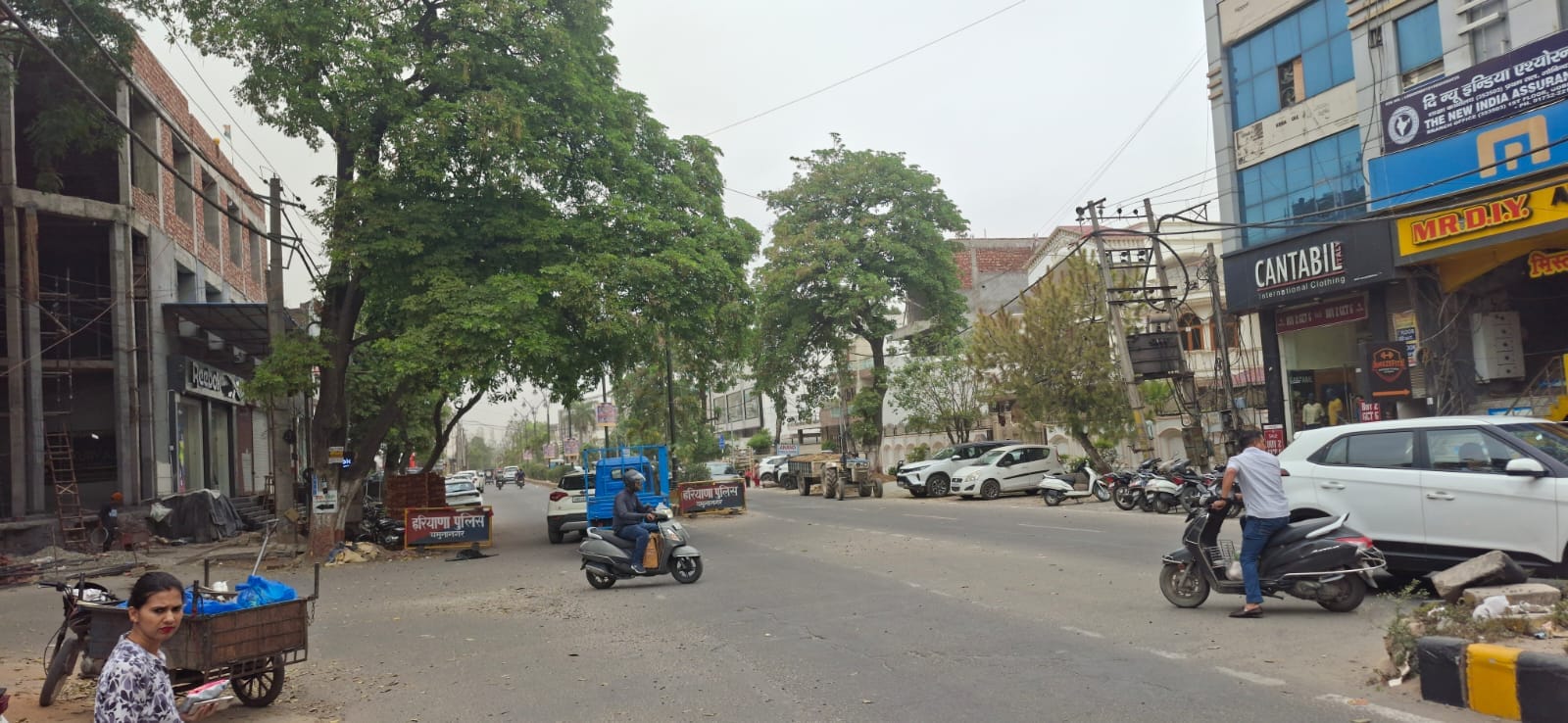 बादल छाने के दौरान शहर की मॉडल टाउन की सड़क से गुजरते लोग। संवाद