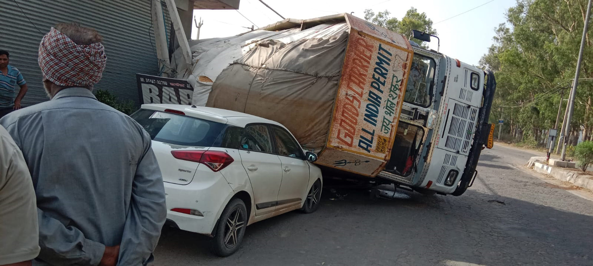 चीका पटियाला रोड़ पर कार के ऊपर पलटा हुआ ट्रक का दृश्य।