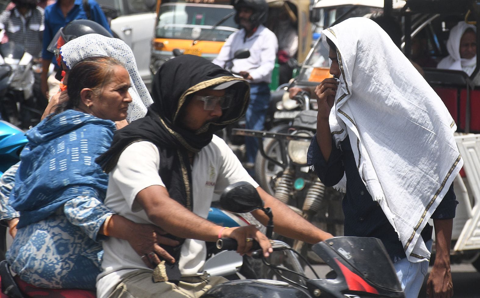 मंगलवार को धूप से बचने की कोशिश करते लोग। 