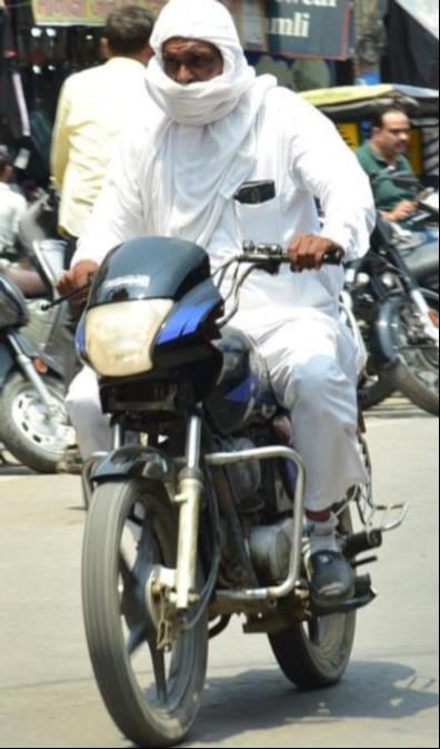 गर्मी से बचने को मुंह ढक्कर जाते युवक।संवाद