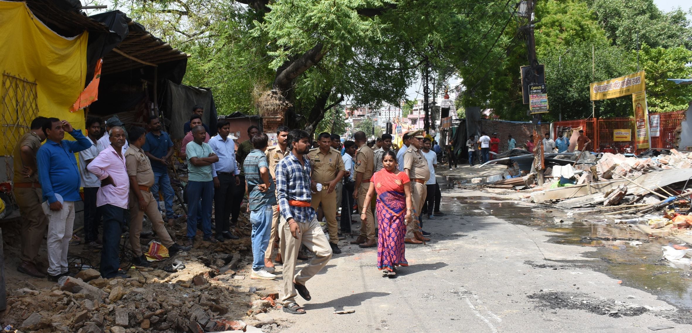 अतिक्रमण ढहाता बुलडोजर और उसे देखते दुकानदार। मौके पर तैनात पुलिस।