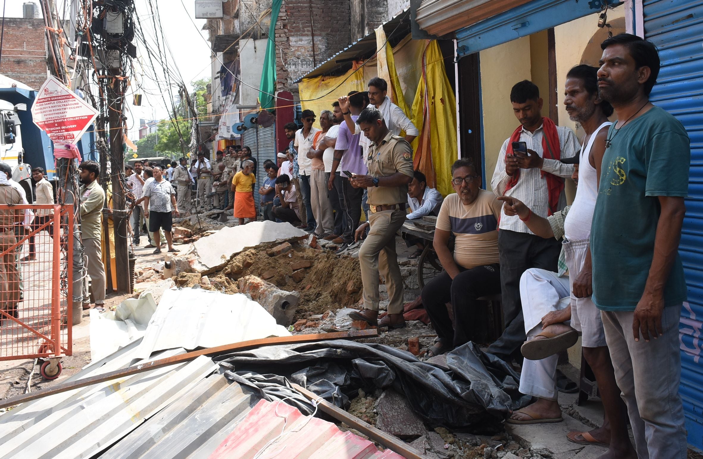 अतिक्रमण ढहाता बुलडोजर और उसे देखते दुकानदार। मौके पर तैनात पुलिस।