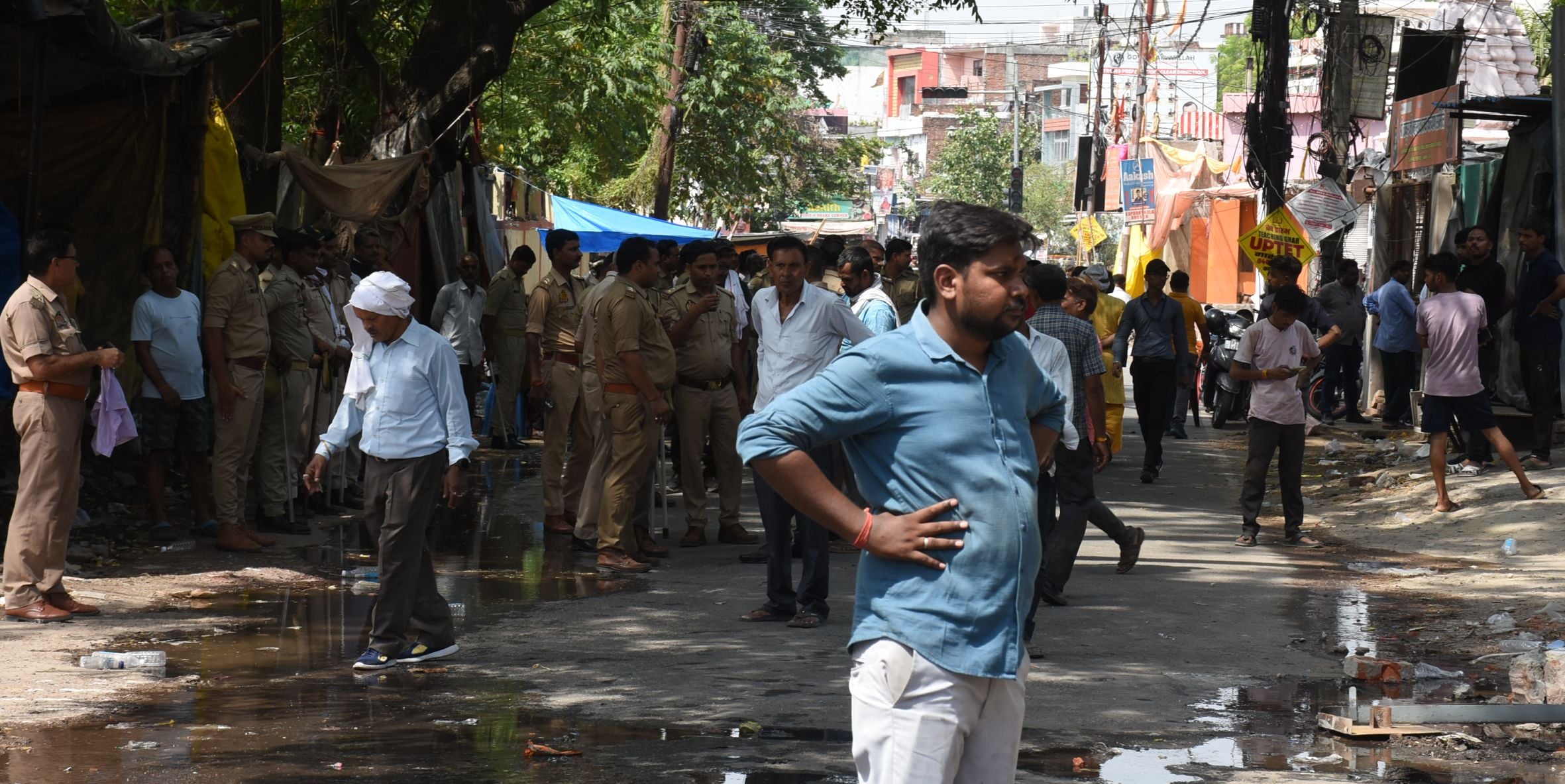अतिक्रमण ढहाता बुलडोजर और उसे देखते दुकानदार। मौके पर तैनात पुलिस।