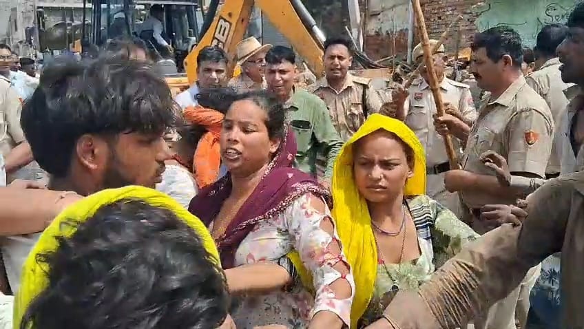 फोटो-65: नगर परिषद की कार्रवाई के दौरान जेसीबी के आगे अड़कर विरोध स्वरूप ईंट उठाकर फेंकती महिला। फोटो-65: नगर परिषद की कार्रवाई के दौरान जेसीबी के आगे अड़कर विरोध स्वरूप ईंट उठाकर फेंकती महिला।