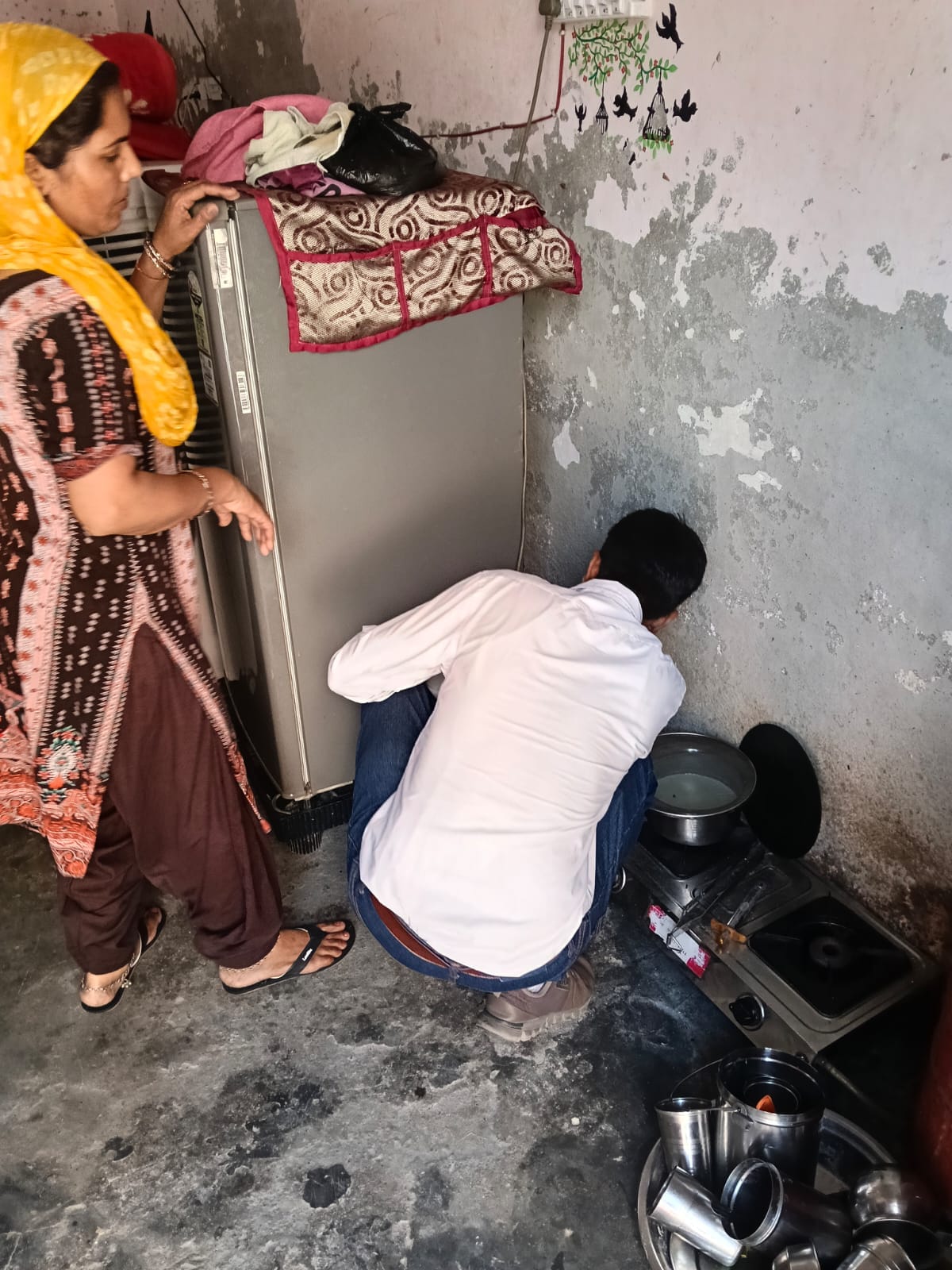 घर में रखे फ्रीज के पीछे जमा होने वाले पानी की जांच करता कर्मचारी। स्वयं
