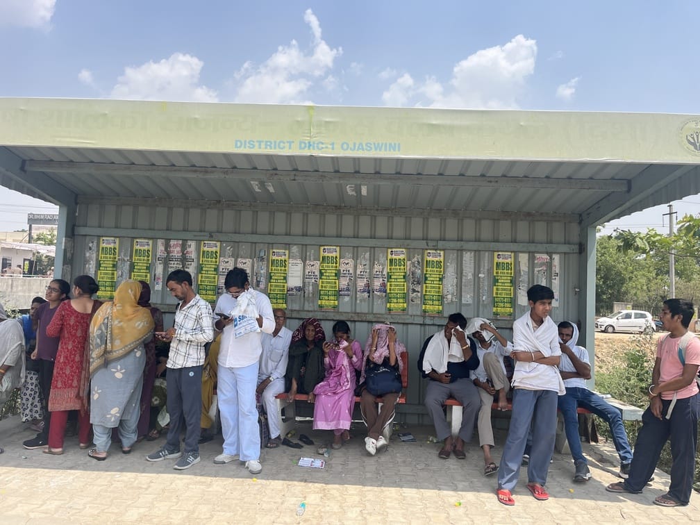 परीक्षा केंद्र से बच्चे के बाहर आने के इंतजार में खेतों में लेटे और बैठे हुए अभिभावक। संवाद परीक्षा केंद्र से बच्चे के बाहर आने के इंतजार में खेतों में लेटे और बैठे हुए अभिभावक। संवाद