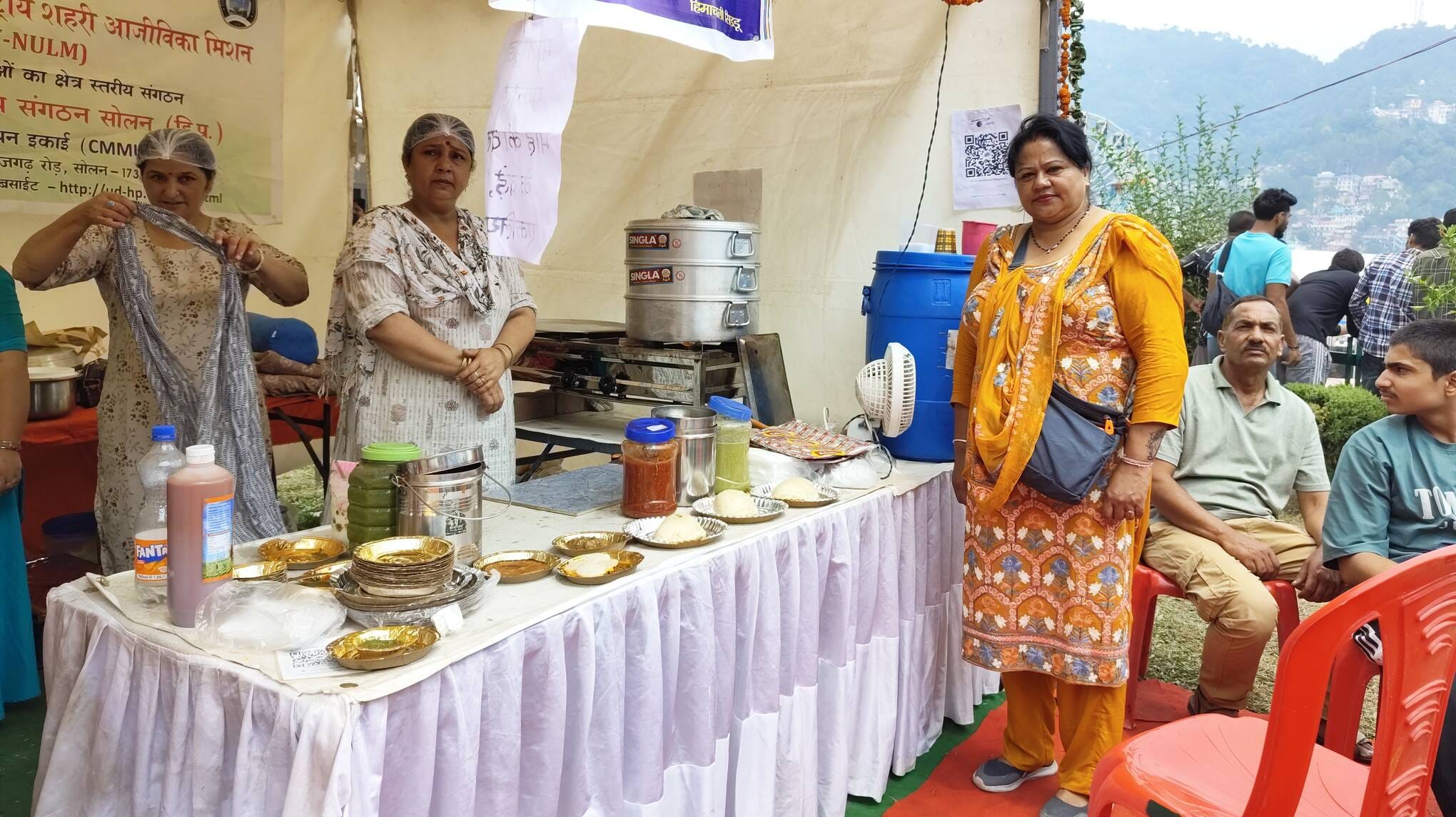 मां शूलिनी मेले के दौरान महिलाओं की ओर से लगाए स्टॉल में पनीर सिड्डू का स्वाद चखते लोग। संवाद मां शूलिनी मेले के दौरान महिलाओं की ओर से लगाए स्टॉल में पनीर सिड्डू का स्वाद चखते लोग। संवाद