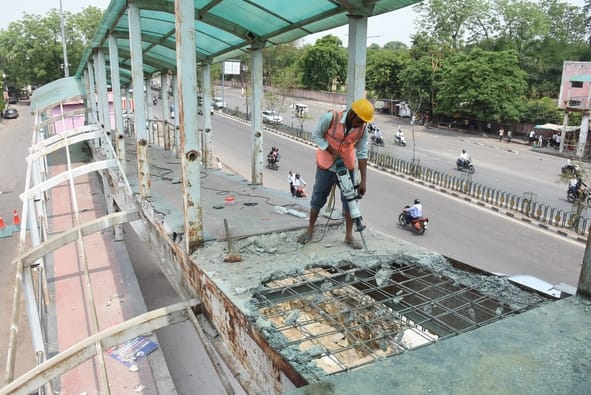 फुट ओवर ब्रिज को तोड़ते श्रमिक।
