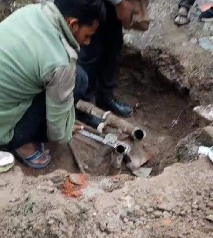 नगर निगम सोलन के वार्ड नं 12 में पाइप लाइन में फंसी बोतल दिखाते कर्मी। संवाद