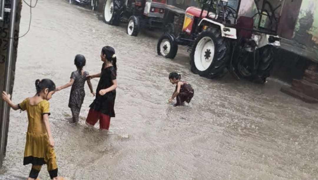 कस्बा जलालाबाद में बारिश के दौरान हुए जलभराव के बीच गुजरते वाहन चालक। संवाद