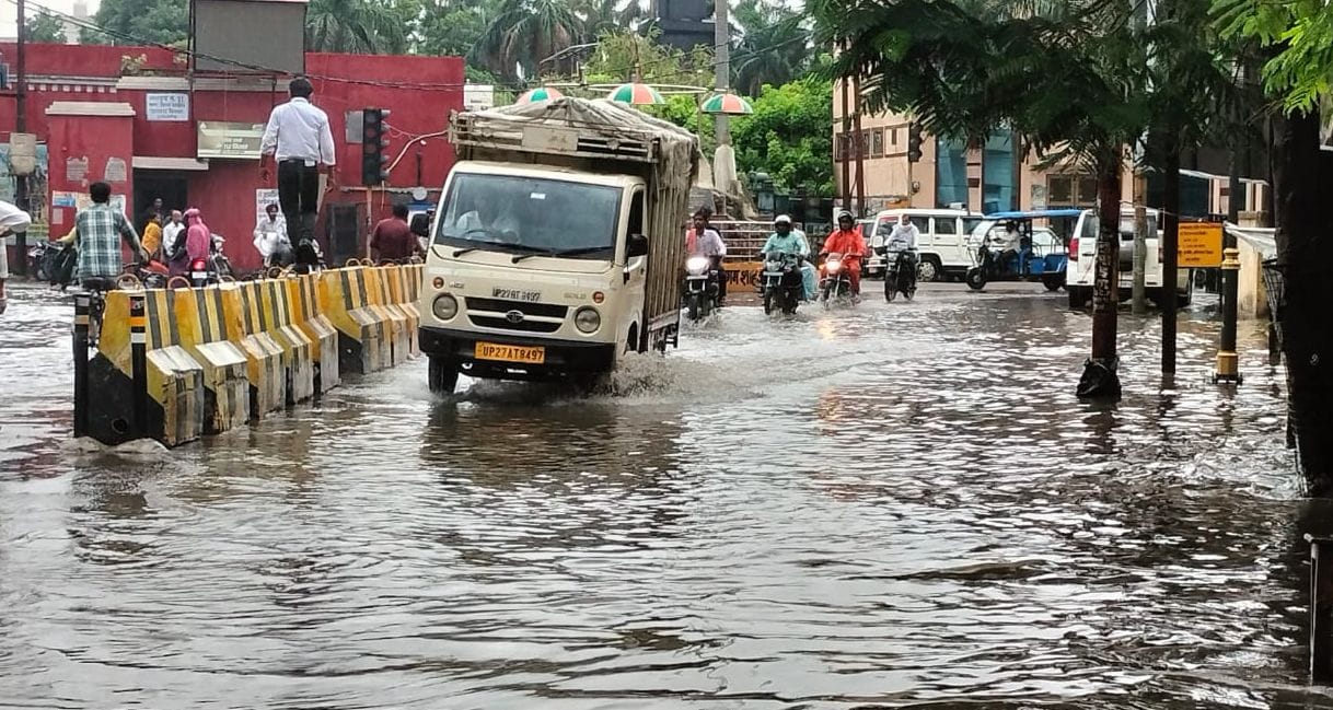 कवि तिराहा पर बारिश से हुए जलभराव में निकलते वाहन। संवाद