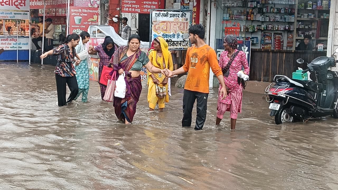 बारिश के बाद जलभराव के बीच गुजरते लोग। बारिश के बाद जलभराव के बीच गुजरते लोग।