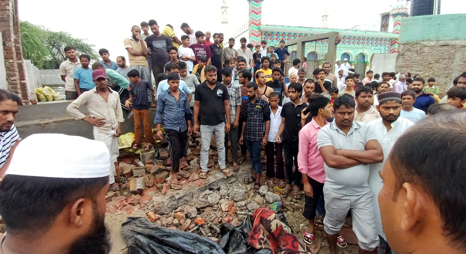 खुर्जा के मुंडाखेड़ा गांव में मस्जिद की दीवार गिरने से घायल बच्चों को अस्पताल ले जाते लोग। संवा