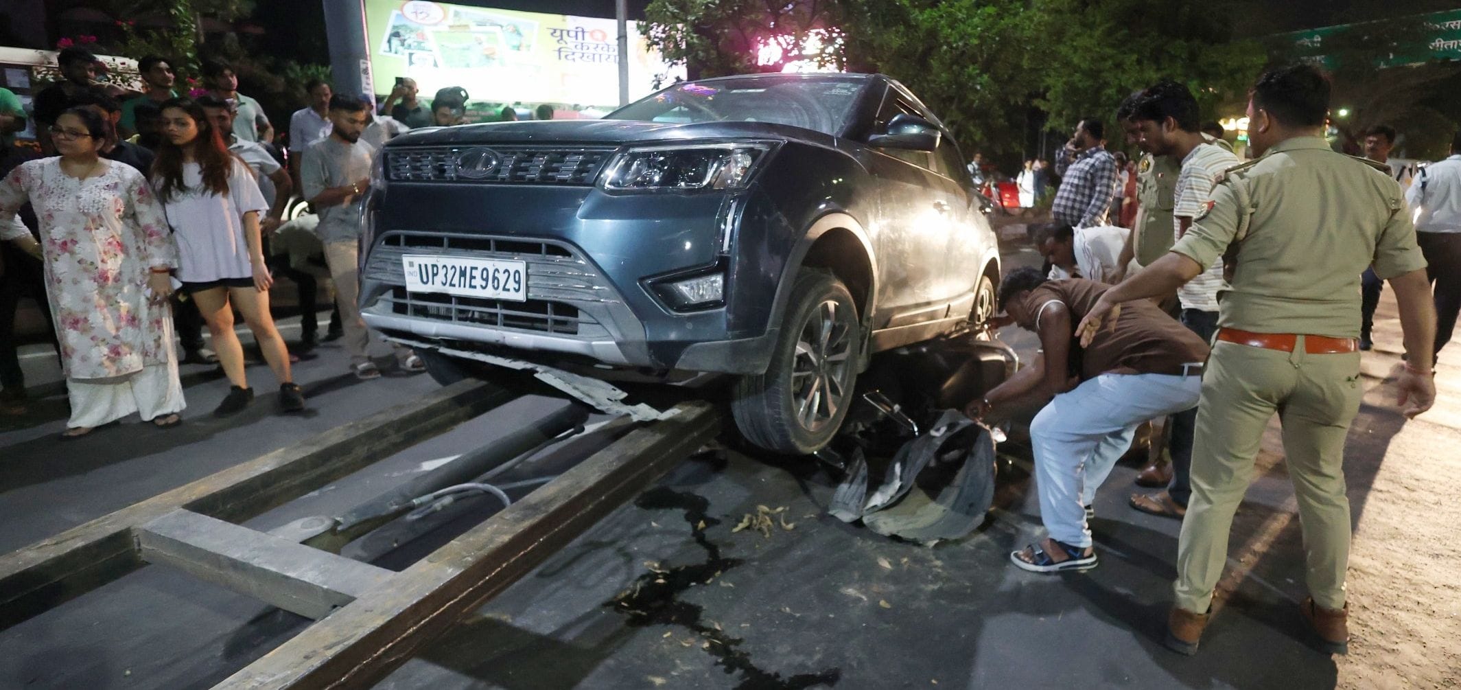 कार के नीचे दबी स्कूटी को निकालते लोग व पुलिस। कार के नीचे दबी स्कूटी को निकालते लोग व पुलिस।