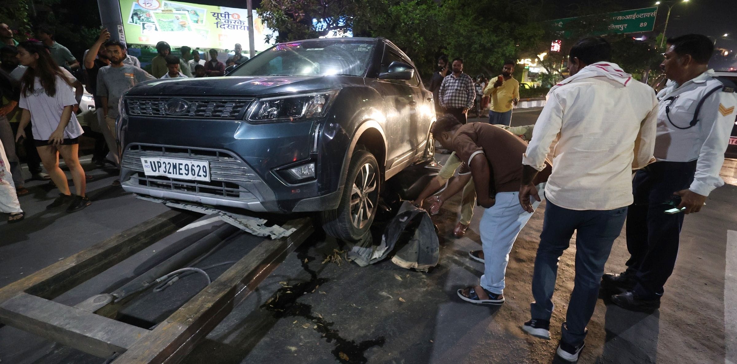 कार के नीचे दबी स्कूटी को निकालते लोग व पुलिस। कार के नीचे दबी स्कूटी को निकालते लोग व पुलिस।