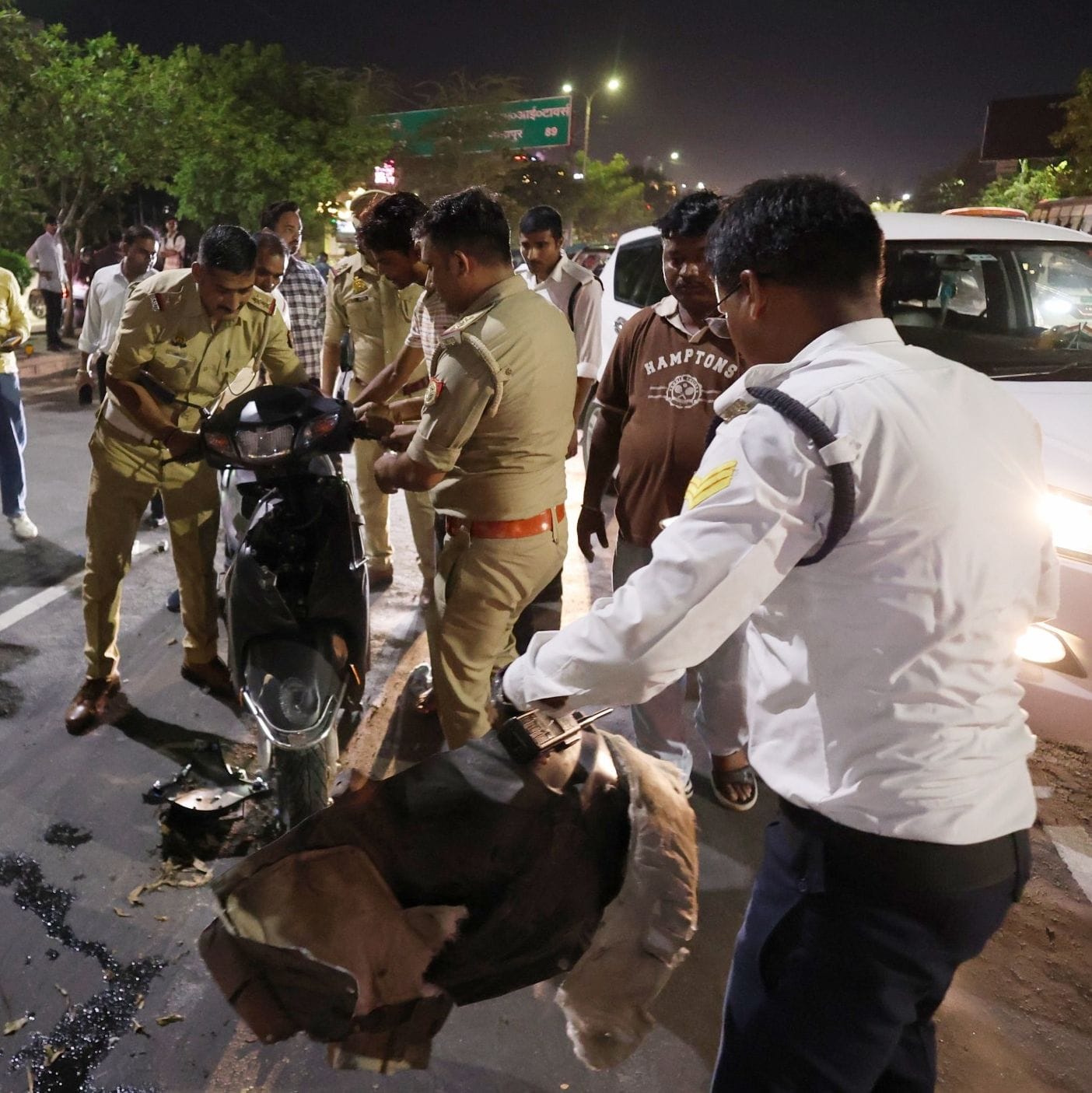 कार के नीचे दबी स्कूटी को निकालते लोग व पुलिस। कार के नीचे दबी स्कूटी को निकालते लोग व पुलिस।