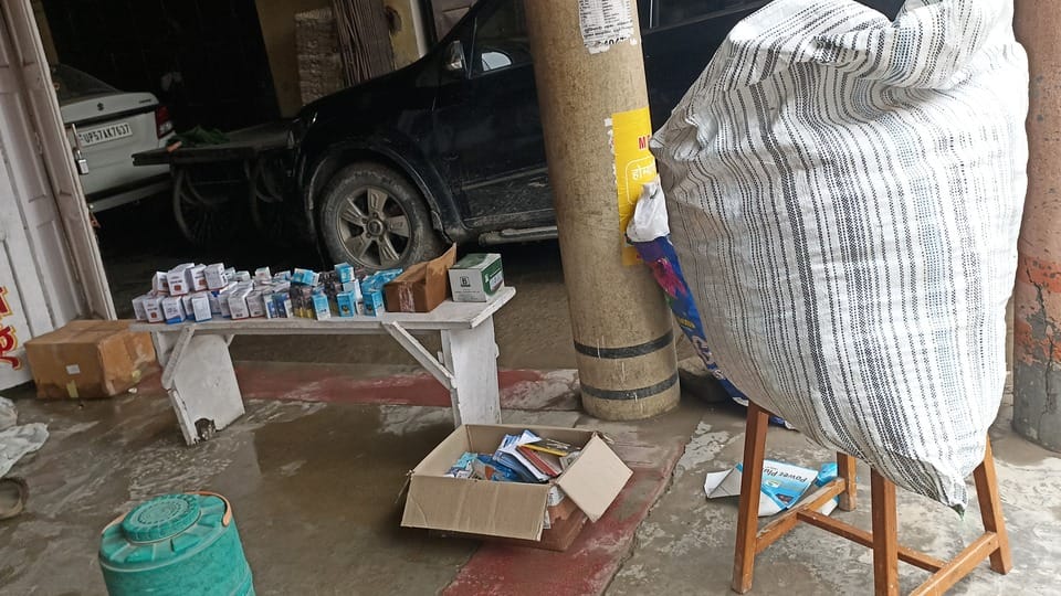 रामकोला रोड पर दुकानों में घुसे पानी को निकालने में जुटे दुकानदार। संवाद