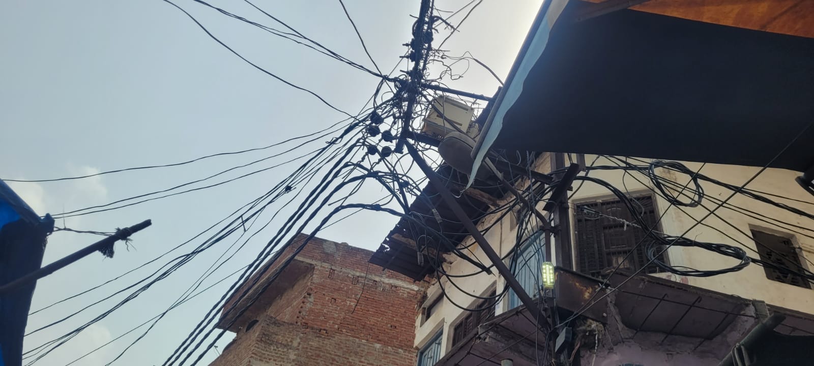 घंटाघर बाजार में बिजली के खंभे पर झूलते हुए तार। संवाद