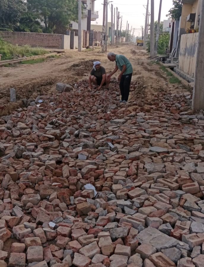 कीचड़ से परेशान लोग खुद ही ईंटें डालकर रास्ता बनाते हुए। कीचड़ से परेशान लोग खुद ही ईंटें डालकर रास्ता बनाते हुए।