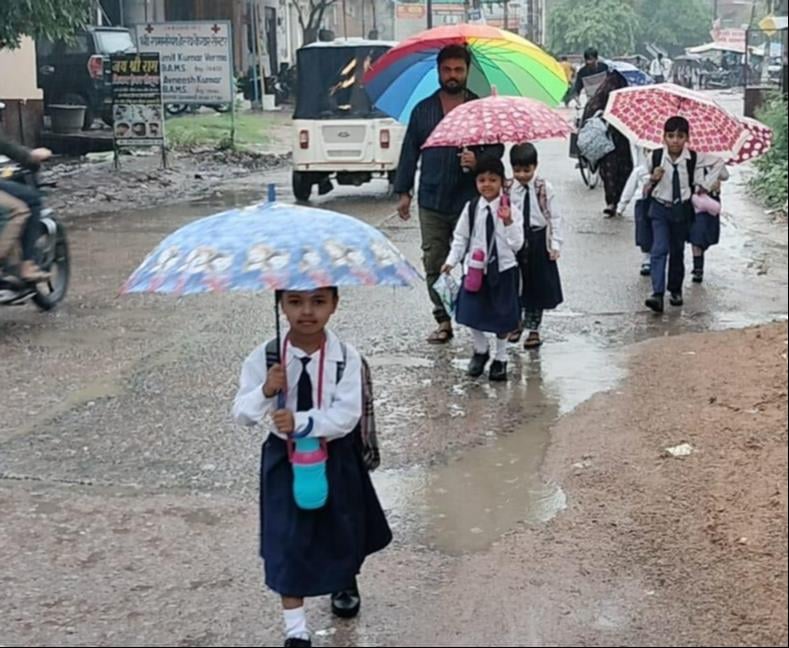 स्कूल की छुट्टी के बाद जीटी रोड से बारिश में छाता लगाकर गुजरते छात्र-छात्राएं। संवाद स्कूल की छुट्टी के बाद जीटी रोड से बारिश में छाता लगाकर गुजरते छात्र-छात्राएं। संवाद
