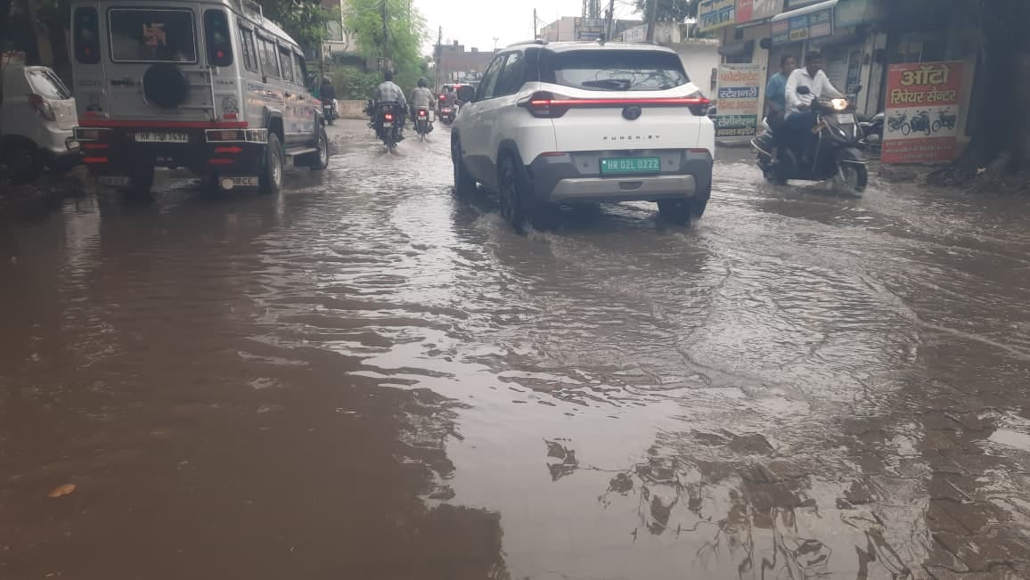 बारिश से बचने के लिए छतरी लेकर मॉडल टाउन से गुजरता व्यक्ति। संवाद बारिश से बचने के लिए छतरी लेकर मॉडल टाउन से गुजरता व्यक्ति। संवाद