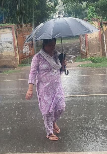 बारिश के बीच छाता लागाकर बच्ची के साथ निकलती महिलाएं। बारिश के बीच छाता लागाकर बच्ची के साथ निकलती महिलाएं।