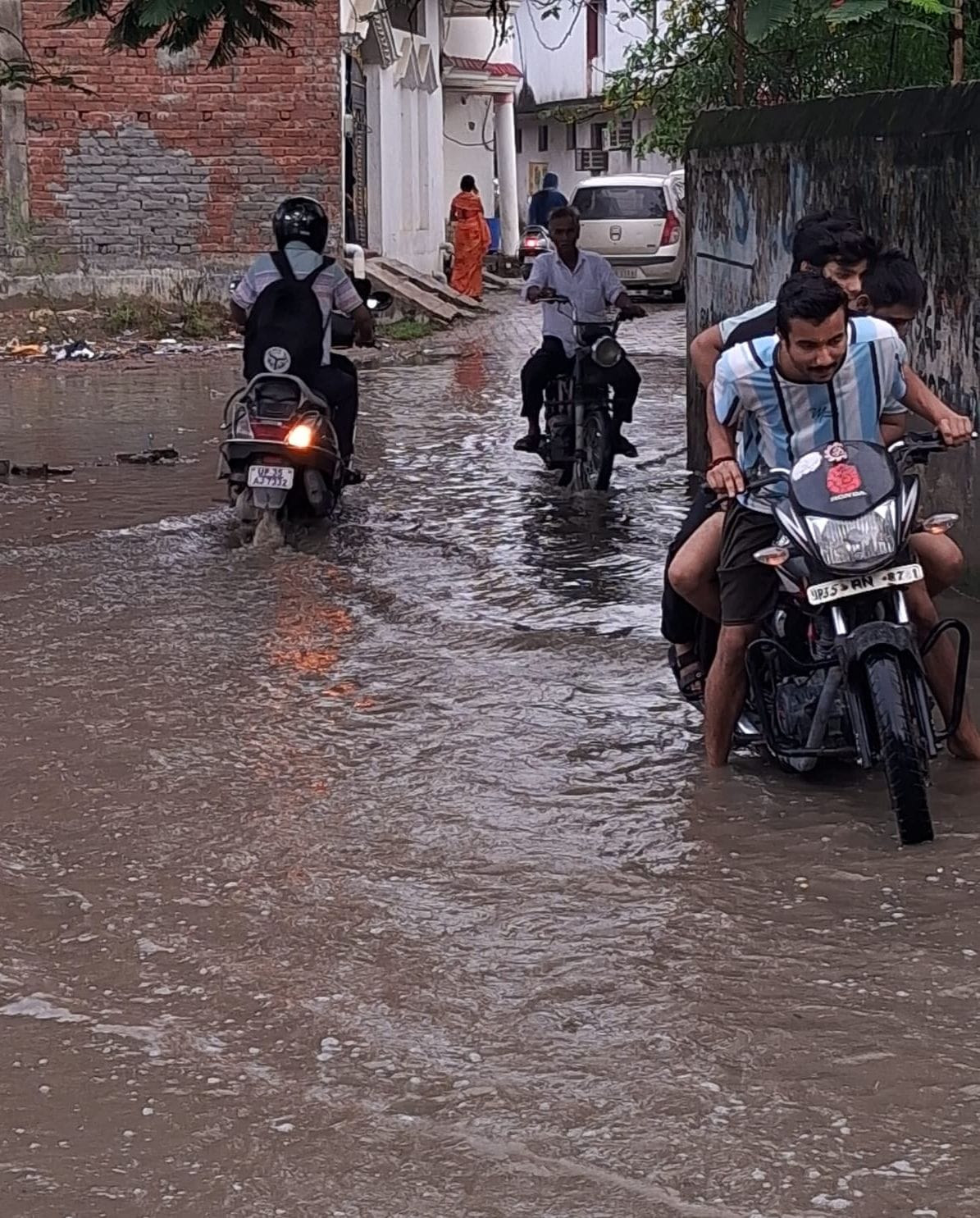 फोटो-1- शहर के मोहल्ला पीतांबर नगर में भरे पानी से बच्चे को लेकर निकलतीं महिला। संवाद