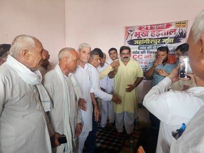 फोटो नंबर 71: धरना स्थल पर अनशन पर बैठे ग्रामीणों को फिरनी सीमेंट की बनाए जाने की जानकारी देते 