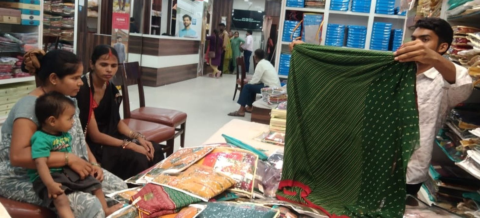 शहर में कपड़ा दुकान पर सावन के लिए साड़ियां पसंद करतीं महिलाएं।