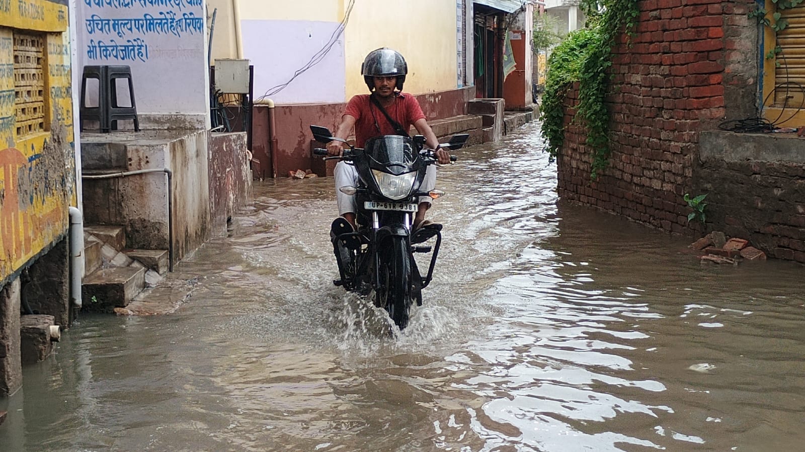 शहर के मिश्रबाजार में सड़क पर जलजमाव के बीच गुजरते बाइक सवार। संवाद