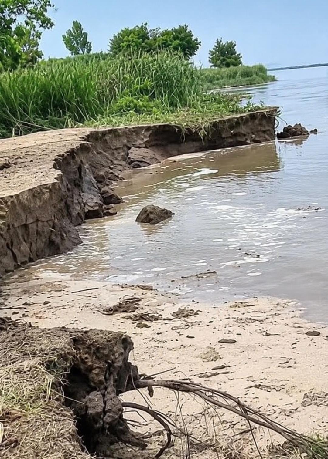 दत्तनगर गांव में कटान की जद में आए आशियाने को उजाड़ते लोग व खेत में कटान करती नदी। संवाद