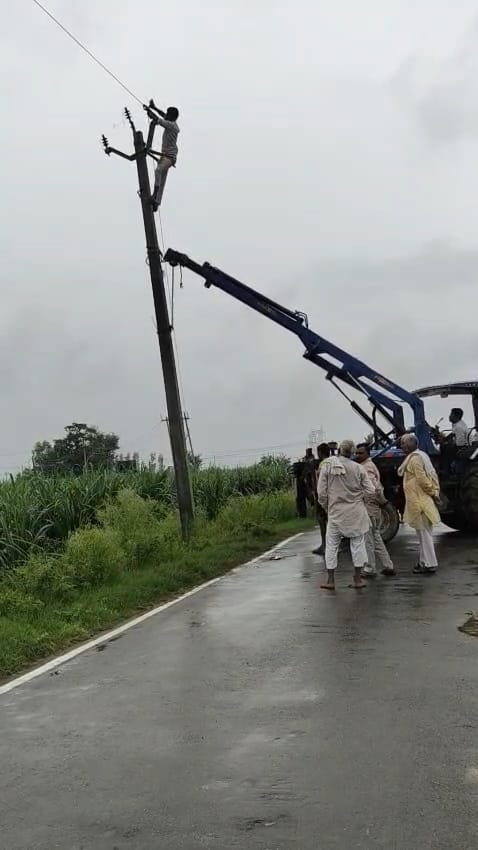दौराला - मिट्टी कटान से झुके पोल सीधा करते विद्युत निगम के कर्मचारी। स्रोत: ग्रामीण